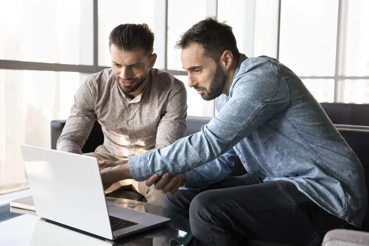 C2C Sibling in Business P1 / Hero Opt 1 Two business partners sitting together, both looking at a laptop screen