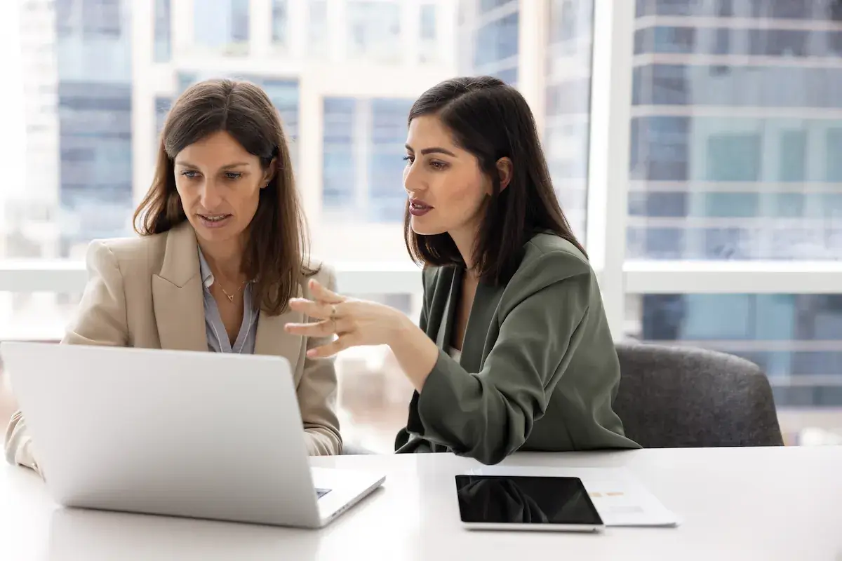 Two business partners working through something together at a laptop