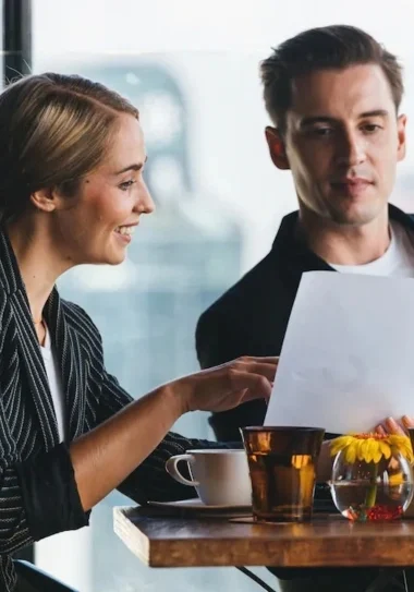 Two business partners going over a document at a cafe table