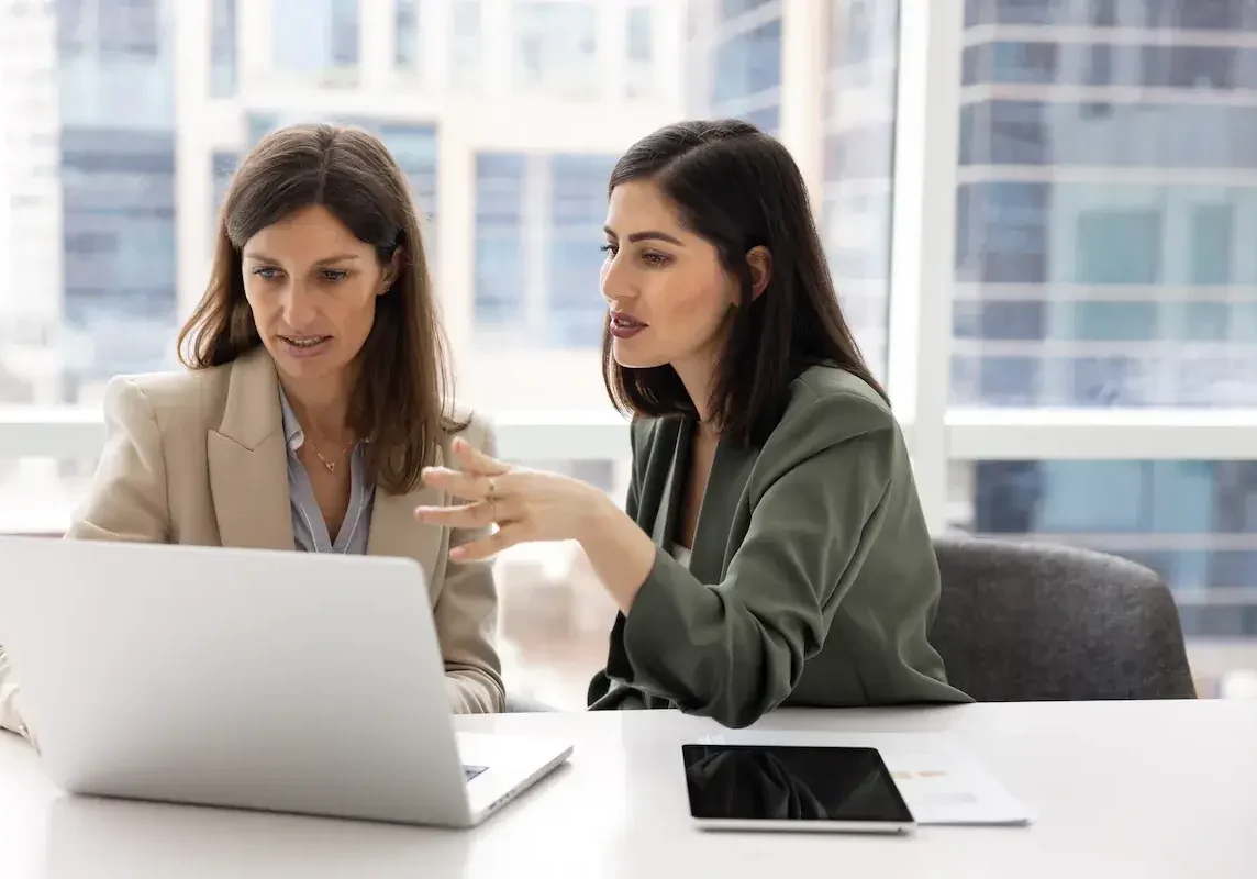 Two business partners working through something together at a laptop