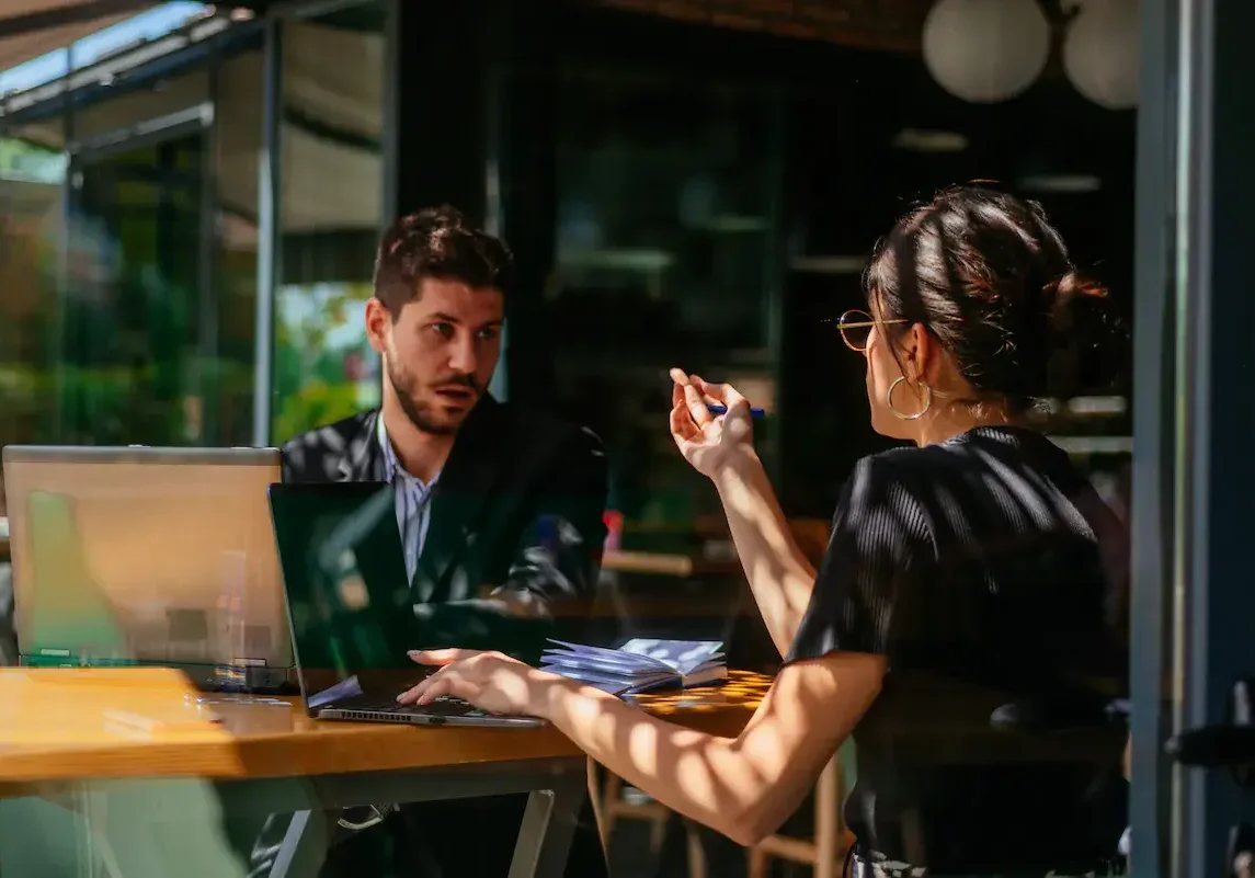 Two business partners in a direct conversation across a table