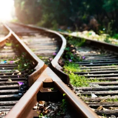 Two railway tracks meeting at a junction, running toward the light